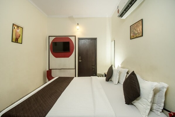 A hotel room with a bed, a red chair, a door, and wall-mounted artwork. - Hotel Amer Classic (Amer)