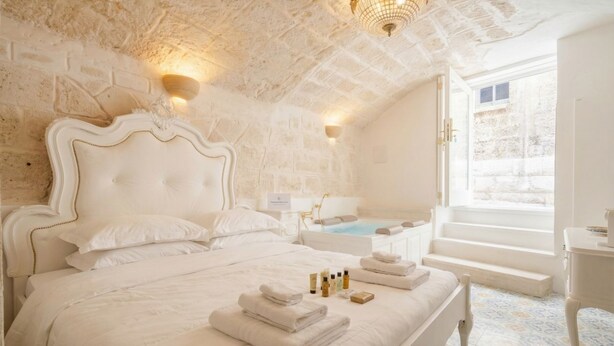 A bedroom with a large bed, a bathtub, and a window with a view. - Reale - Suite with Jacuzzi in the Heart of Monopoli (Monopoli)