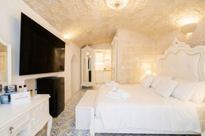 A bedroom with a large bed, a flat-screen TV, a dresser, and a mirror. - Reale - Suite with Jacuzzi in the Heart of Monopoli (Monopoli)