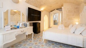 A hotel room with a bed, a TV, a desk with a mirror, and a patterned floor. - Reale - Suite with Jacuzzi in the Heart of Monopoli (Monopoli)