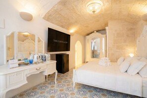 Une chambre d’hôtel avec un lit, une télévision, un bureau avec un miroir et un sol à motifs.
