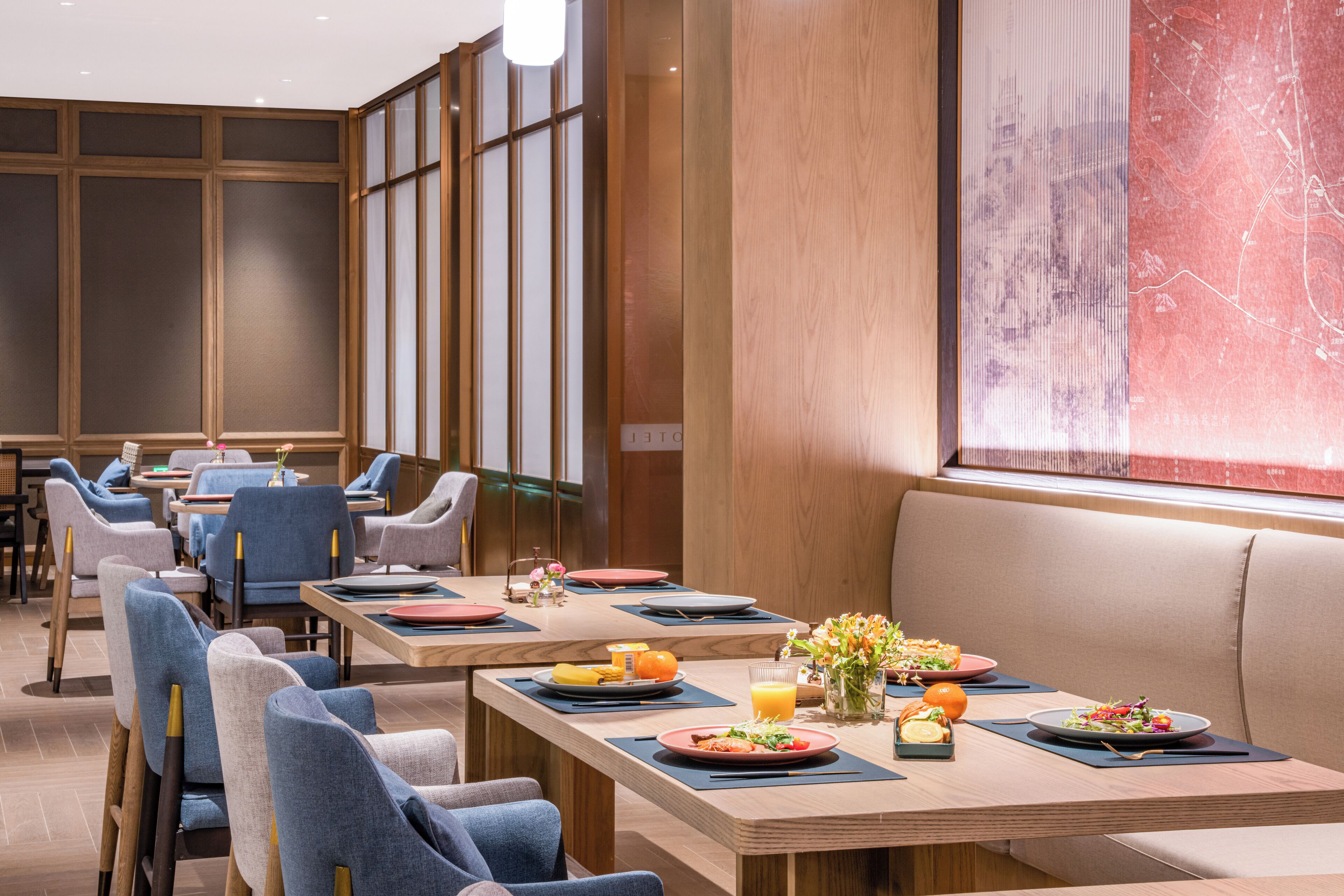 A modern dining area with multiple tables, chairs, and a large window with a cityscape view.