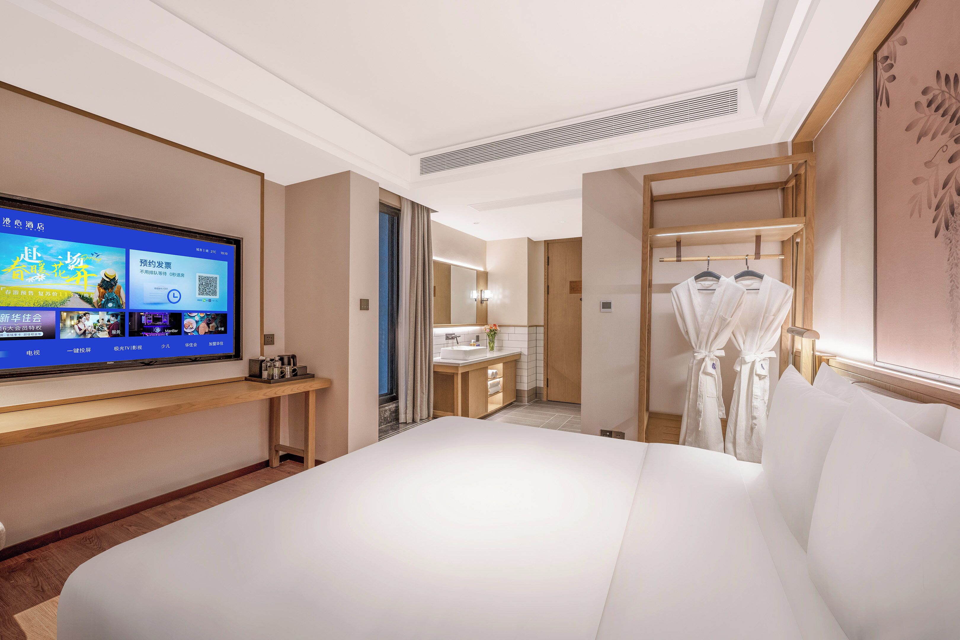 A hotel room with a bed, a television displaying a menu, a bathroom with a sink, and a robe rack.