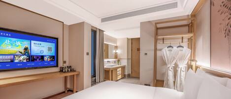 A hotel room with a bed, a television displaying a menu, a bathroom with a sink, and a robe rack.