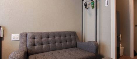 Una sala de estar moderna con un sofá gris, una mesita pequeña y un radiador fijado a la pared.