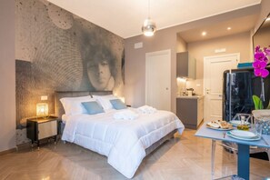 A hotel room with a large bed, bedside table, and a wall-mounted artwork. - Coco - Elegance Boudoir (Bari)