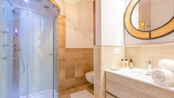 Un bagno moderno con cabina doccia in vetro, un mobile lavabo in legno e uno specchio rotondo.