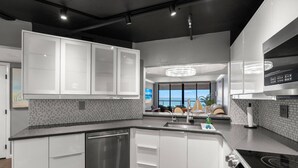 Une cuisine moderne avec des meubles blancs, un lave-vaisselle en acier inoxydable et une cuisinière noire.