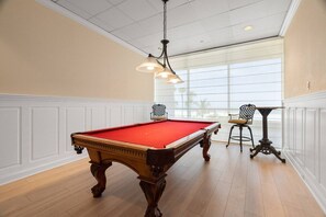 A pool table with a red felt surface, a hanging light fixture, and two chairs with metal frames. - Beachfront! Amazing Views! 6B Crescent Beach Club (Clearwater)