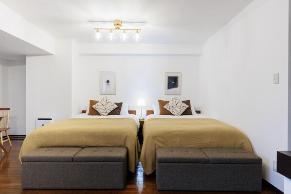 Une chambre d’hôtel avec deux lits, un bureau et une chaise.