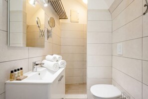 Un baño moderno con lavamanos, espejo y retrete.