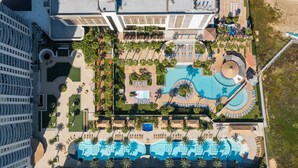 Vista aérea de un complejo turístico con varias piscinas, palmeras y un gran conjunto de edificios.