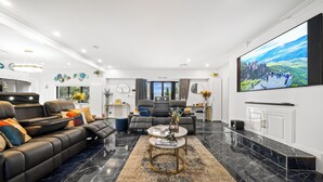 Un salon moderne avec un canapé en cuir, une table basse et un grand téléviseur à écran plat fixé au mur.