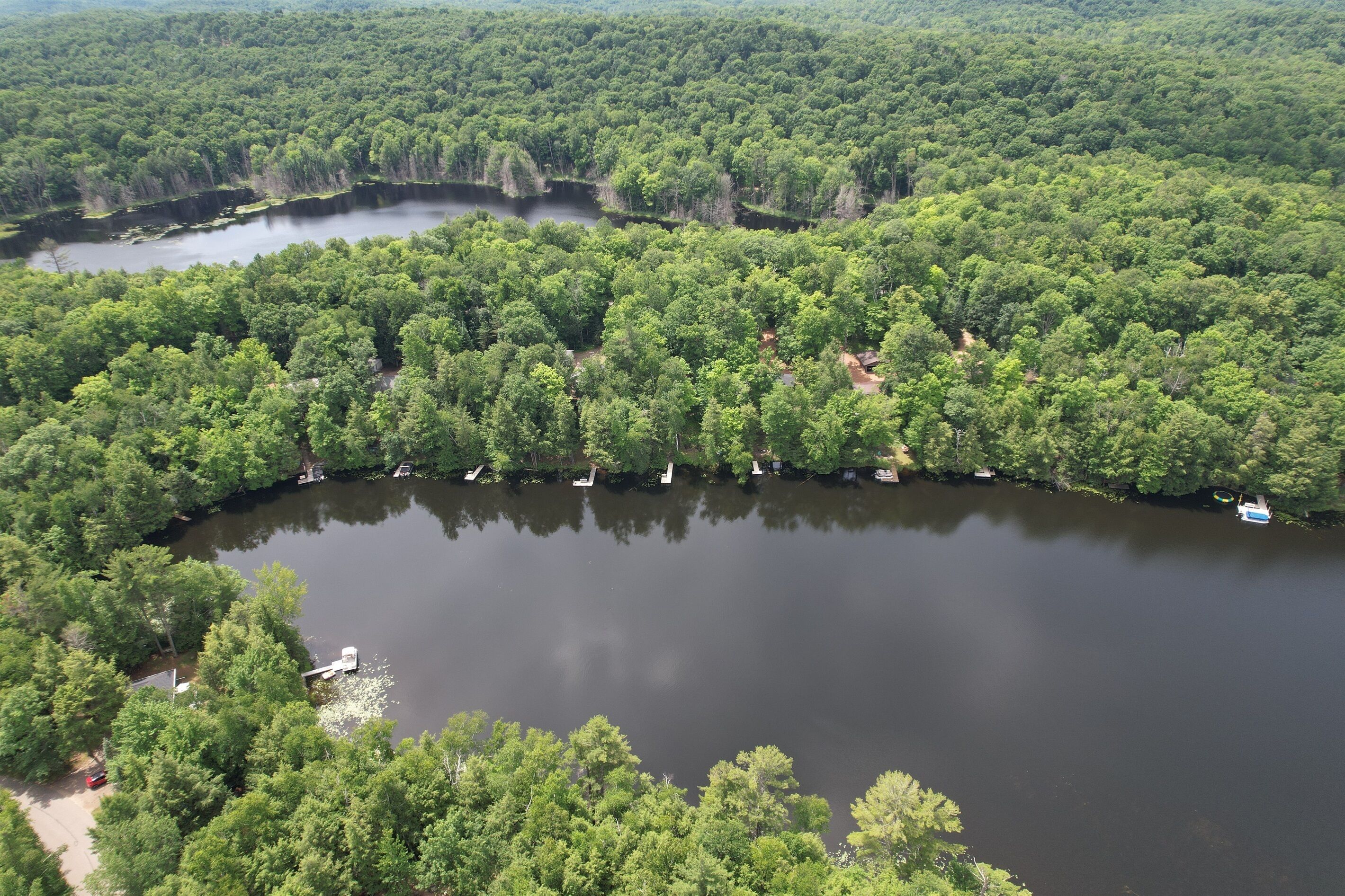 Vista aérea de un lago rodeado de bosque denso, con varias embarcaciones amarradas a la orilla.