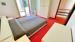 A bedroom with a bed, a wardrobe, and a desk.
