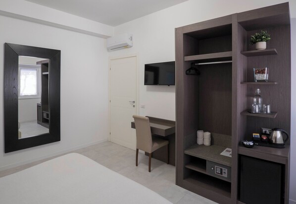 A modern hotel room with a desk, chair, wardrobe, and built-in shelves. - RAPHAEL ROOM (Roma)