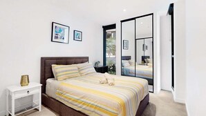 A modern bedroom with a large bed, a nightstand, and a sliding door leading to a balcony. - The Valley Pad | 2BR with Style (Brisbane)