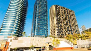 Three high-rise buildings with a modern design, featuring curved glass facades and a mix of reflective and patterned surfaces. - The Valley Pad | 2BR with Style (Brisbane)