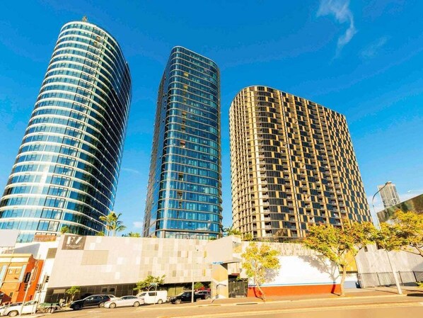 Three high-rise buildings with a modern design, featuring curved glass facades and a mix of reflective and patterned surfaces. - The Valley Pad | 2BR with Style (Brisbane)