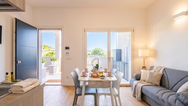 A modern living room with a dining area, a sofa, and a balcony with a view.