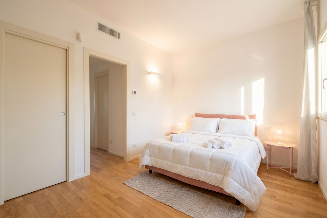 Una camera da letto con un letto, un comodino, una porta e una finestra.