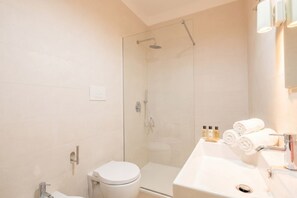 A modern bathroom with a glass-enclosed shower, a white sink, and neatly rolled towels.