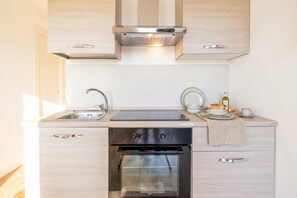 A modern kitchen with a stainless steel range hood, double sink, oven, and light wood cabinetry. - Dimora Anna - Beachfront Apartment (Bari)
