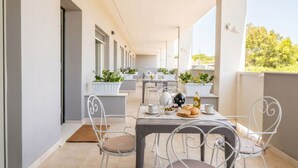 A covered outdoor dining area with tables and chairs, potted plants, and a view of the surrounding area. - Dimora Anna - Beachfront Apartment (Bari)