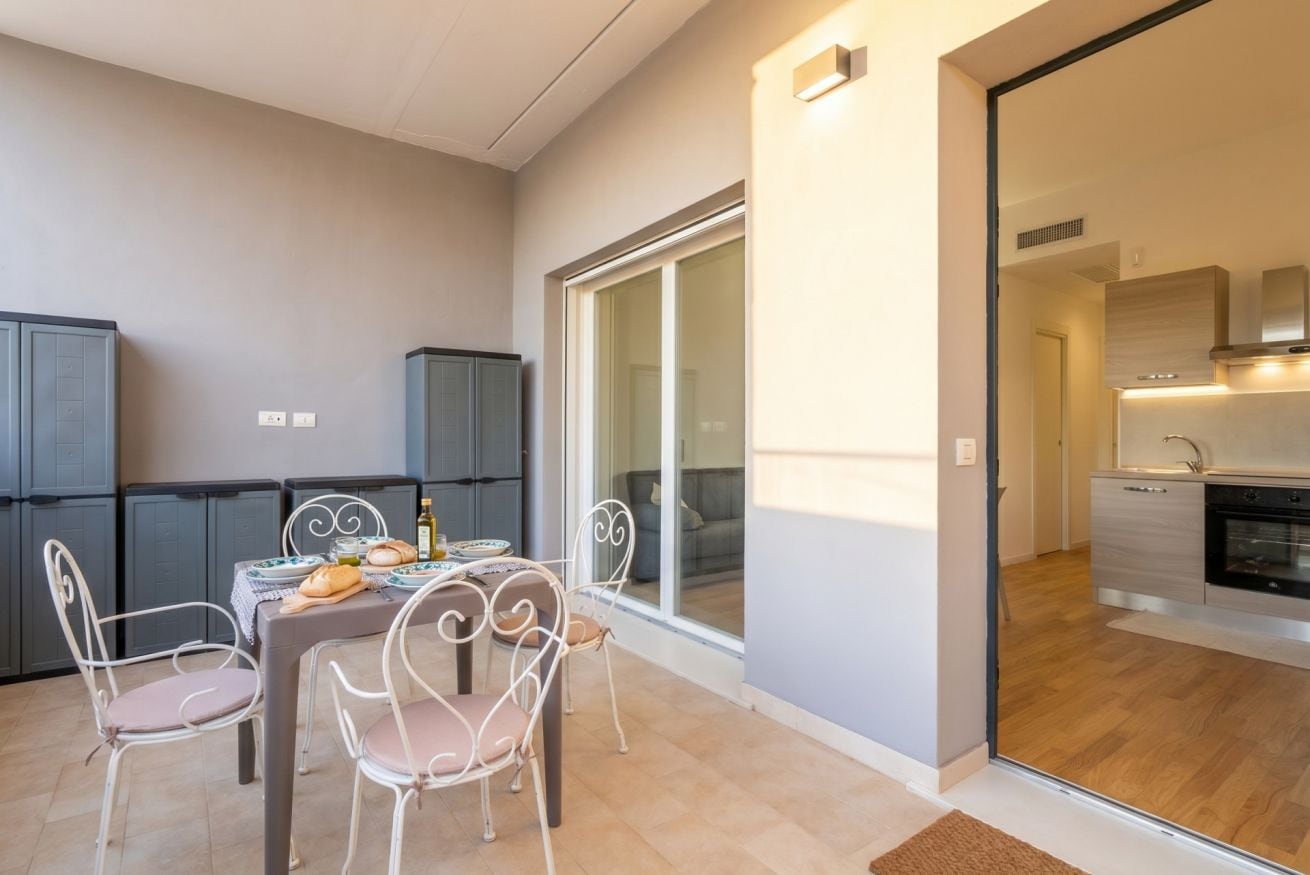 A modern apartment with a dining area, kitchen, and sliding glass doors leading to a balcony.