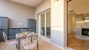 A modern apartment with a dining area, kitchen, and sliding glass doors leading to a balcony. - Dimora Anna - Beachfront Apartment (Bari)