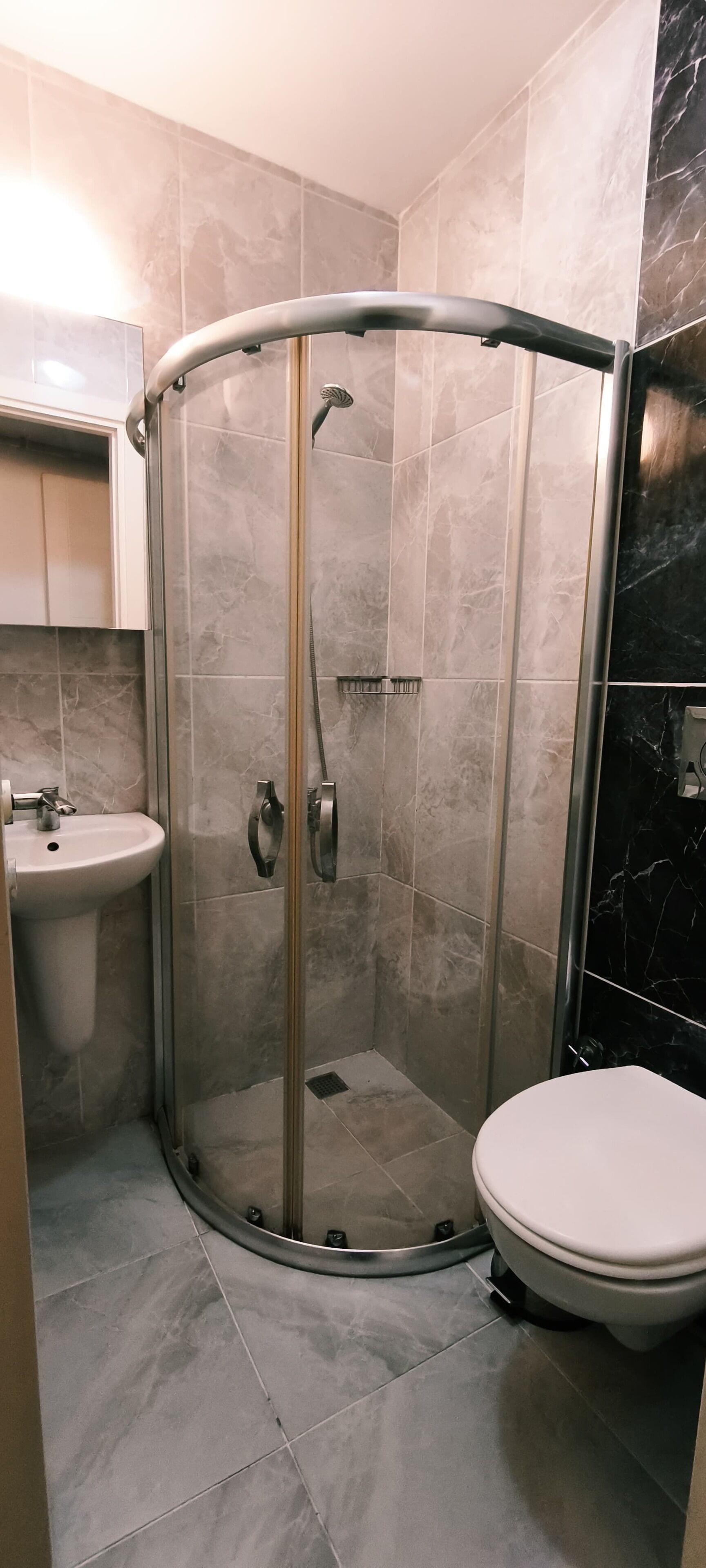 A bathroom with a glass-enclosed shower, a sink, and a toilet.