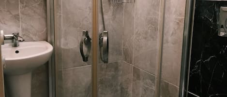 A bathroom with a glass-enclosed shower, a sink, and a toilet.
