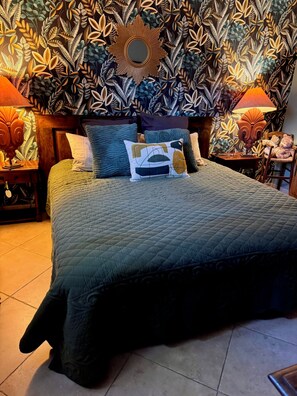 Een bed met een gewatteerde sprei, meerdere kussens en een hoofdbord met een spiegel.