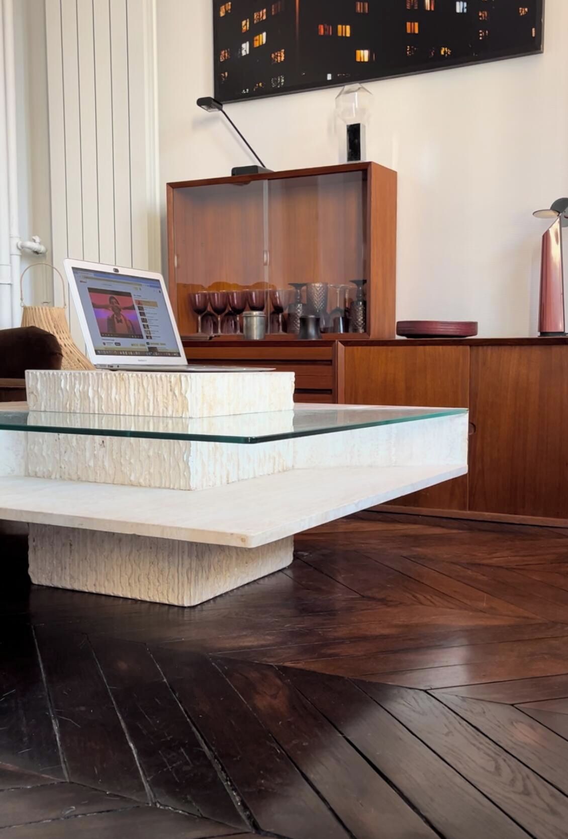 A modern kitchen with a glass-top island, wooden cabinets, and a laptop on the island.