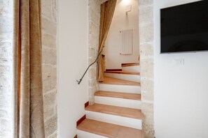 A staircase with stone walls and a flat-screen TV mounted above it.