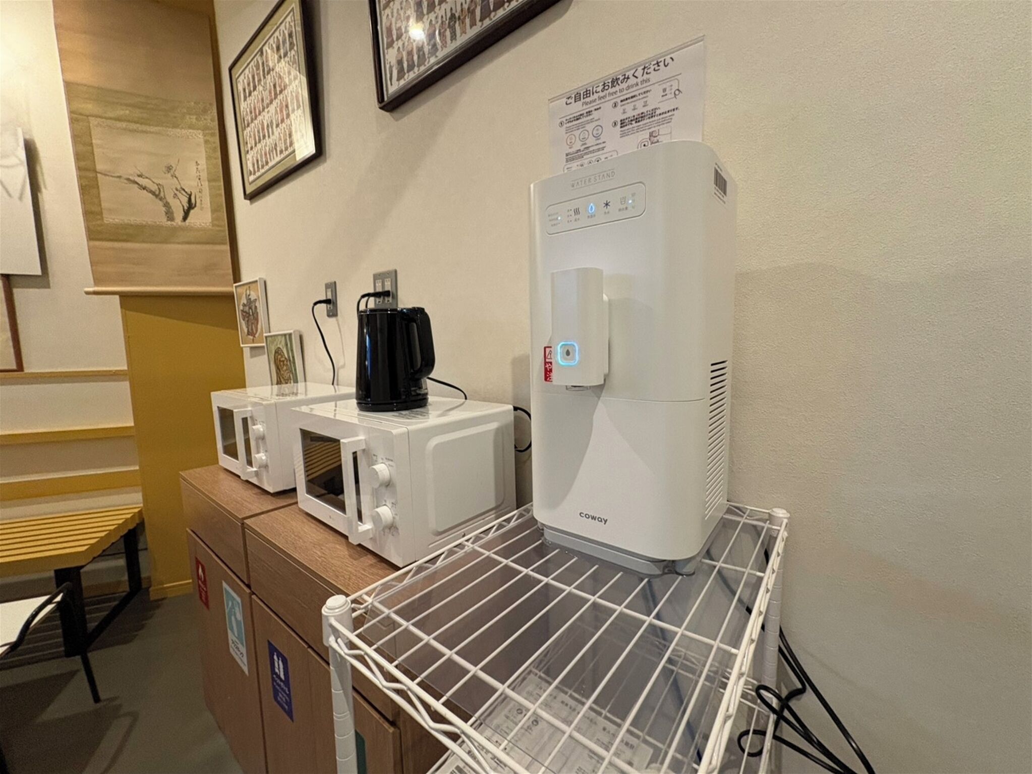 Eine Küchenzeile mit Kaffeemaschine, Mikrowelle und Wasserspender auf einer weißen Arbeitsplatte.