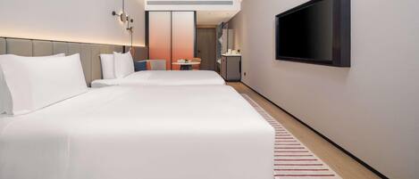 A modern hotel room with a large bed, a TV mounted on the wall, and a small table with a chair.