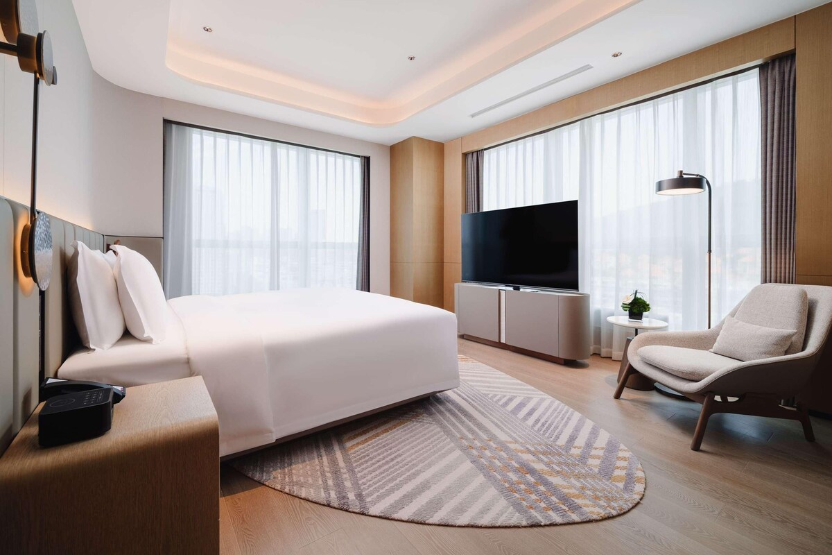 Une chambre d’hôtel moderne équipée d’un grand lit, d’un téléviseur à écran plat, d’un bureau et d’une chaise.