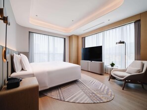 Une chambre d’hôtel moderne équipée d’un grand lit, d’un téléviseur à écran plat, d’un bureau et d’une chaise.