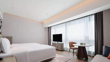 Ein modernes Hotelzimmer mit einem großen Bett, einem Fernseher, einem kleinen Tisch und einer Couch.