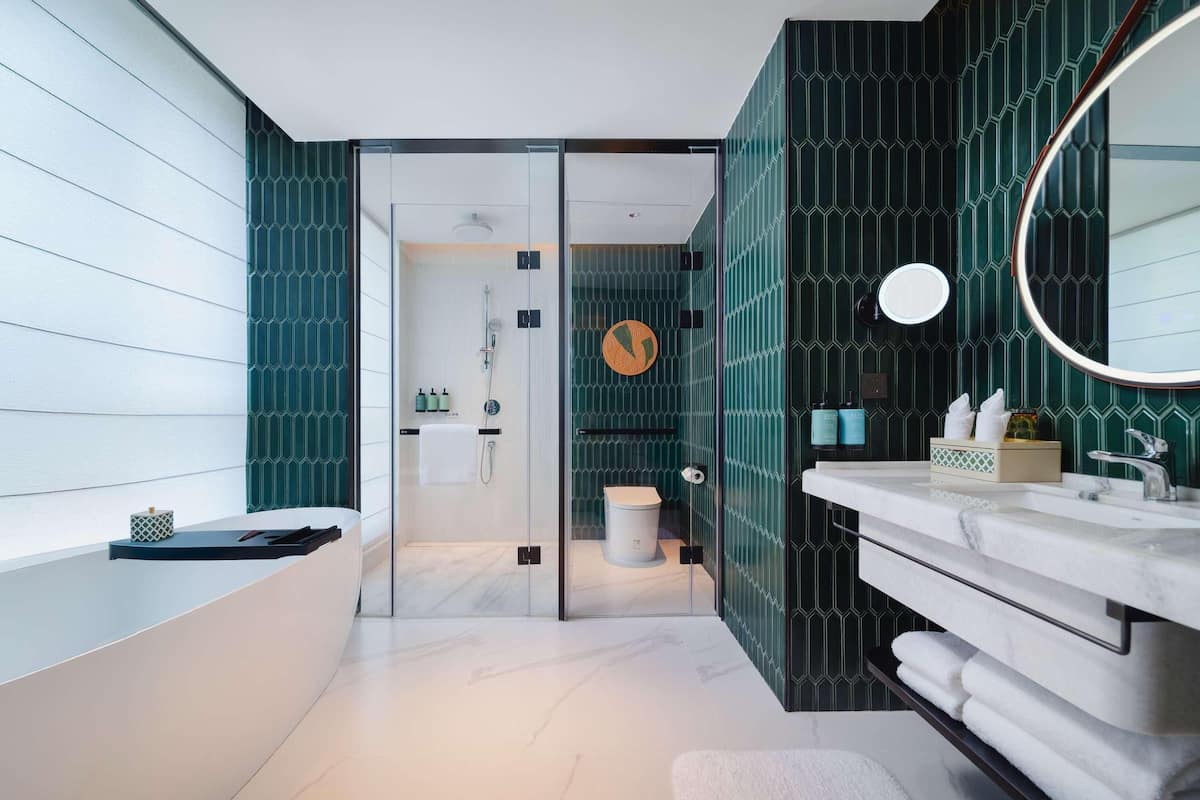 Ein modernes Badezimmer mit einer gläsernen Duschkabine, einem Waschtisch mit Spiegel und einer Toilette.