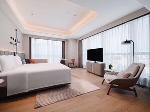 Une chambre d’hôtel moderne équipée d’un grand lit, d’une télévision, d’un bureau et d’une chaise.