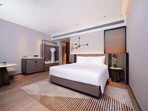 Una habitación de hotel moderna con una cama grande, un escritorio, un tocador y una mesita con una planta.