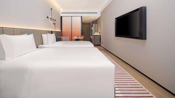 A modern hotel room with a large bed, a TV mounted on the wall, and a small table with a chair.
