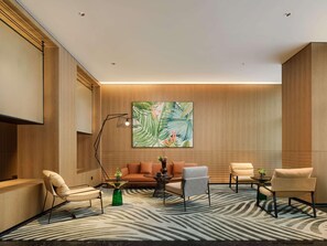 Un área de lounge moderna con alfombra de estampado de cebra, paneles de pared de madera y un cuadro de gran tamaño con motivos tropicales.