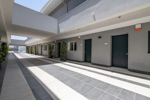 A modern building with a covered walkway, potted plants, and doors.