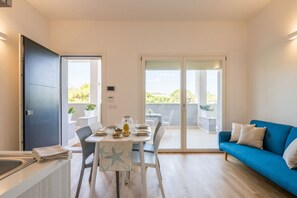 A modern living room with a dining area, a blue sofa, and a balcony with a view.