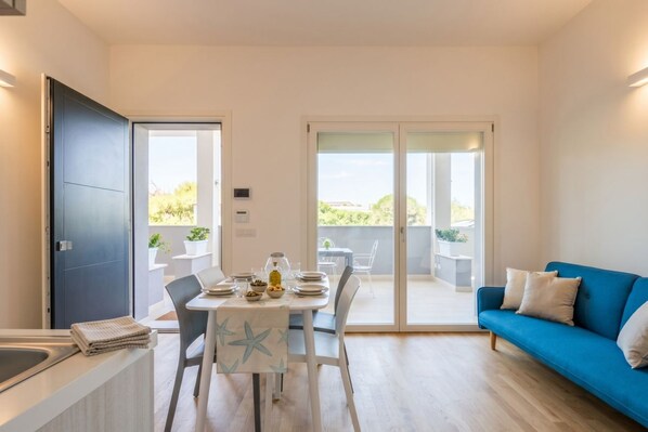 A modern living room with a dining area, a blue sofa, and a balcony with a view. - Domus Blaesia - Cozy Stay (Bari)