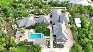 Um imóvel residencial com várias coberturas, piscina e vegetação ao redor.