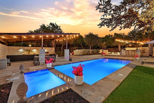 Piscina com deck de pedra, área de estar externa e luzes de corda.